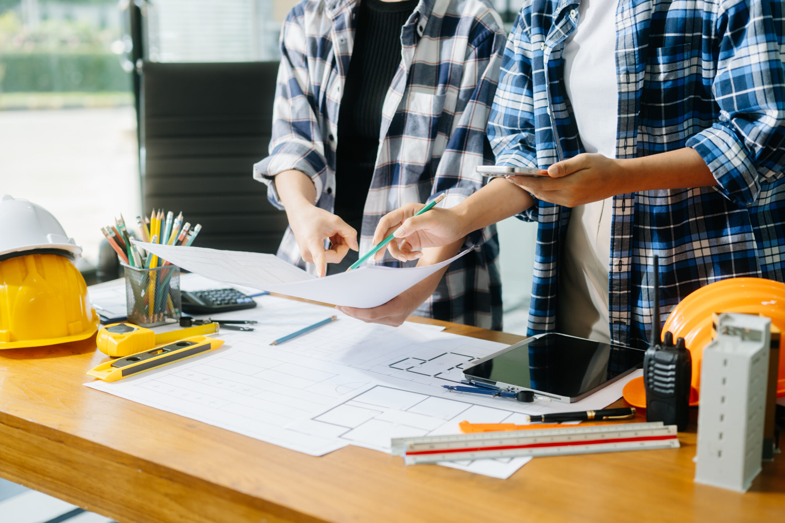 Creative architect projecting on the big drawings with architectural project at construction site at desk in modern office
